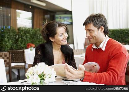 Mid adult couple sitting in a restaurant and looking at each other