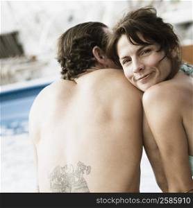 Mid adult couple sitting on the ledge of a swimming pool