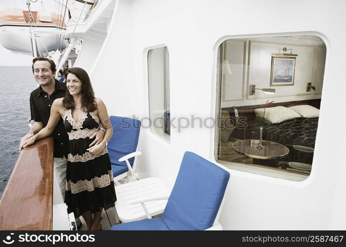 Mid adult couple standing at the railing of a sailing ship and smiling