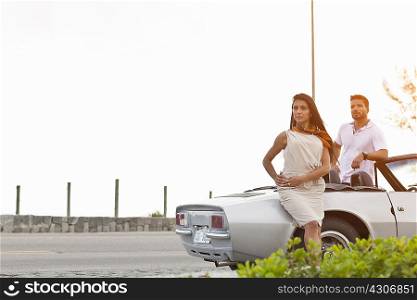 Mid adult couple standing by convertible car by side of road