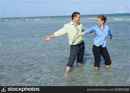 Mid adult couple standing on the beach with their arms outstretched