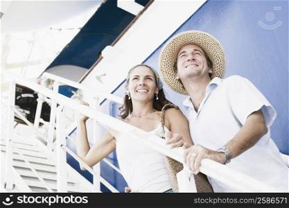 Mid adult couple standing on the staircase of a cruise ship and smiling