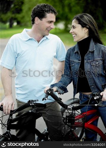 Mid adult couple standing with their bicycles and looking at each other