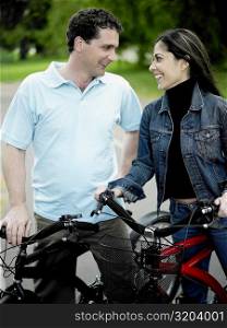 Mid adult couple standing with their bicycles and looking at each other