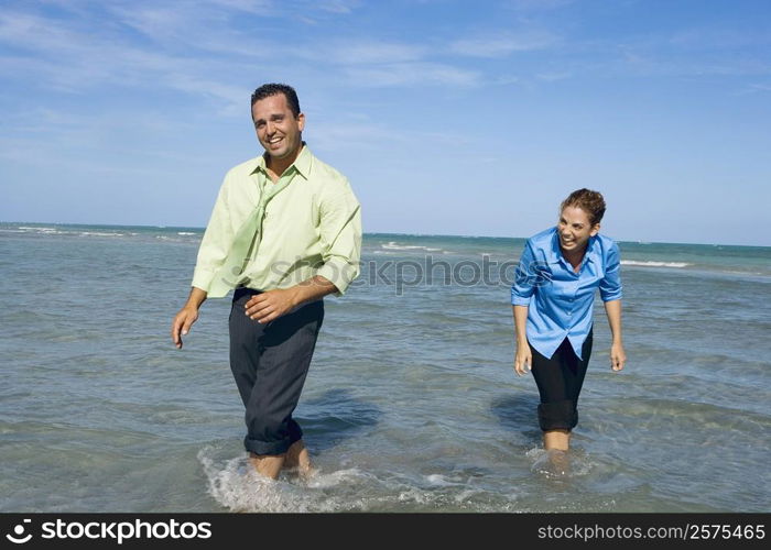 Mid adult couple wading on the beach and smiling