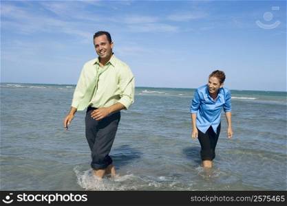 Mid adult couple wading on the beach and smiling