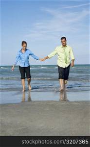 Mid adult couple walking on the beach with holding each others hands