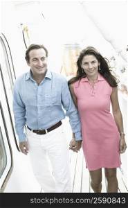 Mid adult couple walking with holding hands of each other on the deck of a cruise ship