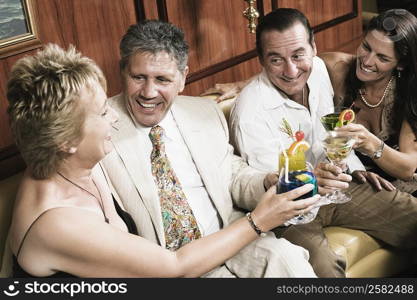 Mid adult couple with a mature woman and a senior man toasting glasses of cocktail