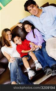 Mid adult couple with their children sitting on a couch and watching television