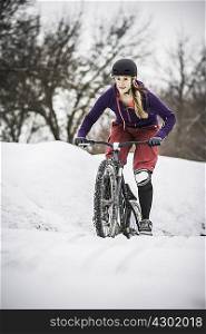 Mid adult female mountain biker struggling to ride through snow