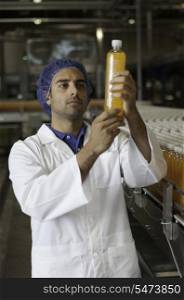 Mid adult industrial worker examining bottle in factory
