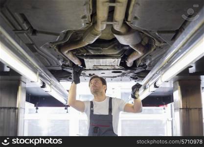 Mid adult male repair worker repairing car in workshop