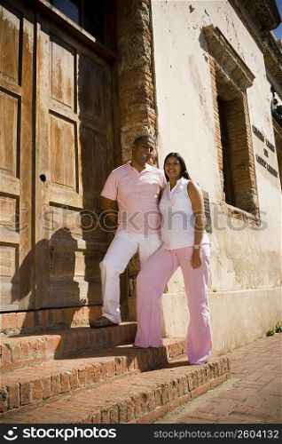 Mid adult man and a pregnant young woman standing on steps in front of a door, Santo Domingo, Dominican Republic