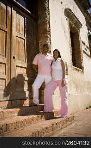 Mid adult man and a pregnant young woman standing on steps in front of a door, Santo Domingo, Dominican Republic