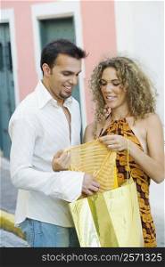 Mid adult man and a teenage girl holding a shopping bag and examining a top