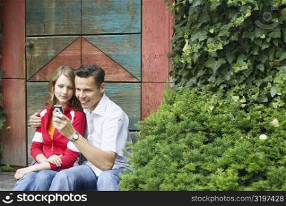 Mid adult man and a teenage girl looking at a mobile phone