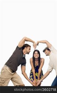 Mid adult man and a young man making a heart shape in front of a young woman