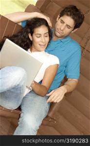 Mid adult man and a young woman sitting on a porch swing with a laptop