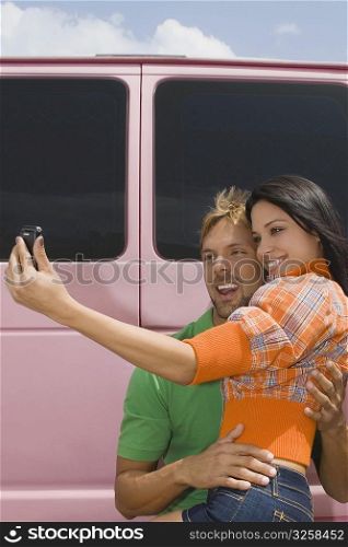 Mid adult man and a young woman taking a photograph of themselves
