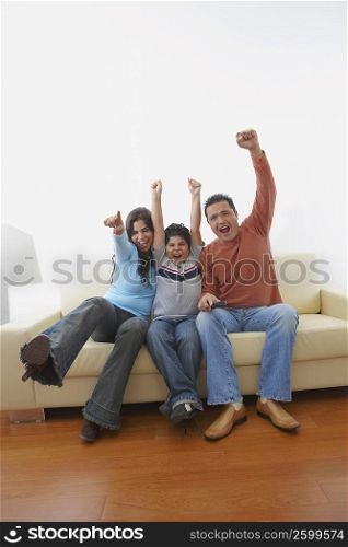 Mid adult man and a young woman with their son sitting on a couch and shouting