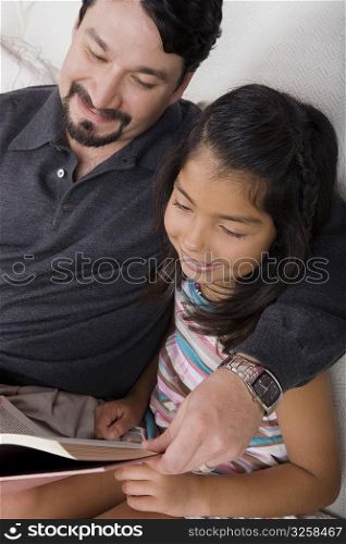 Mid adult man and his daughter reading a book