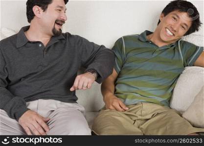 Mid adult man and his son sitting on a couch and smiling