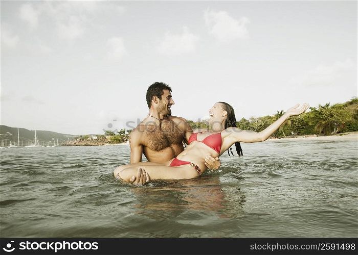 Mid adult man carrying a mid adult woman in water