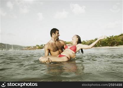 Mid adult man carrying a mid adult woman in water