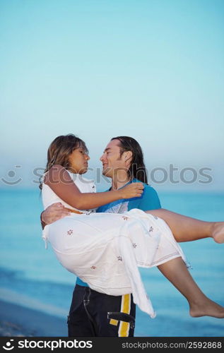 Mid adult man carrying a young woman on the beach