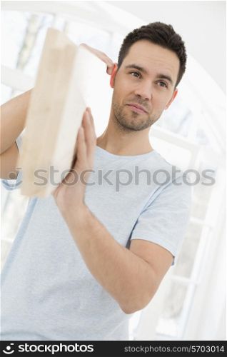 Mid-adult man carrying wooden plank on shoulder