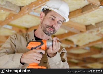 mid-adult man drilling hole in wall