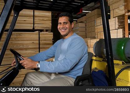 Mid-adult man driving forklift at warehouse