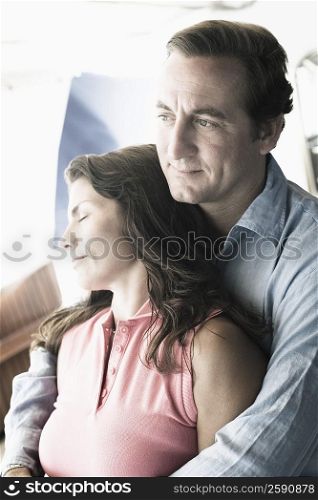 Mid adult man embracing a mid adult woman from behind