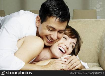 Mid adult man embracing a young woman lying on a couch
