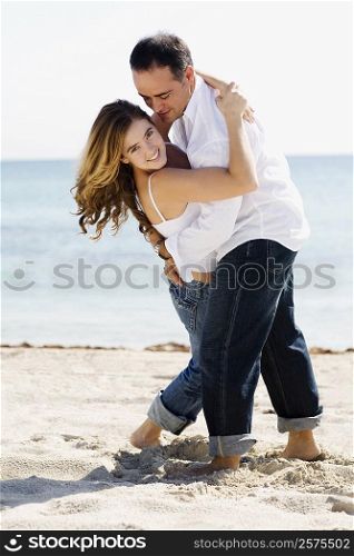 Mid adult man embracing a young woman on the beach