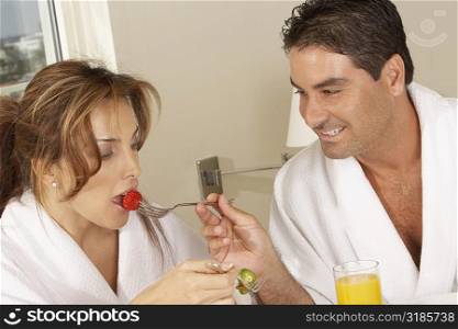 Mid adult man feeding a mid adult woman a strawberry