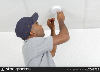 mid-adult man fixing light bulb wiring in new house