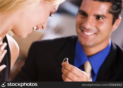 Mid adult man giving an engagement ring to a young woman