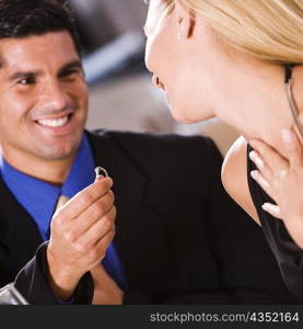 Mid adult man giving an engagement ring to a young woman