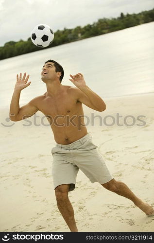 Mid adult man heading a soccer ball on the beach