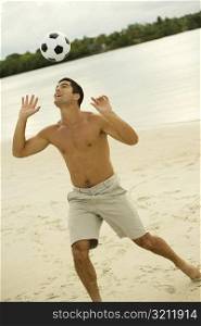 Mid adult man heading a soccer ball on the beach