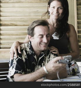 Mid adult man holding a digital camera with a mid adult woman standing beside him