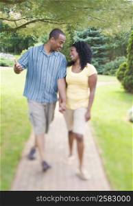 Mid adult man holding hands of a young woman and walking in a lawn