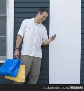 Mid adult man holding shopping bags and a mobile phone