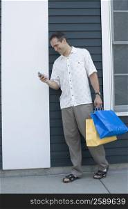 Mid adult man holding shopping bags and a mobile phone