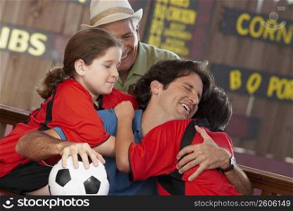Mid adult man hugging his son in a restaurant with his father and daughter behind him