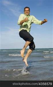 Mid adult man jumping on the beach