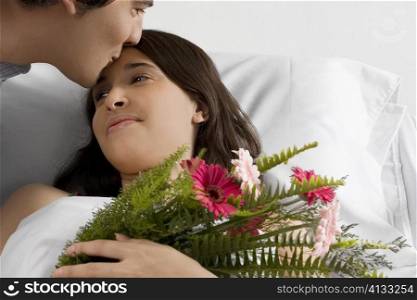 Mid adult man kissing a young woman in a hospital ward