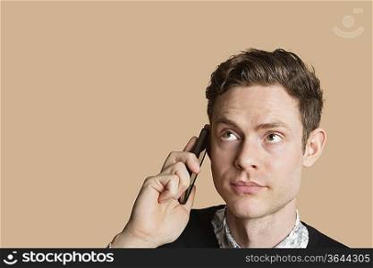 Mid adult man listening to mobile phone over colored background